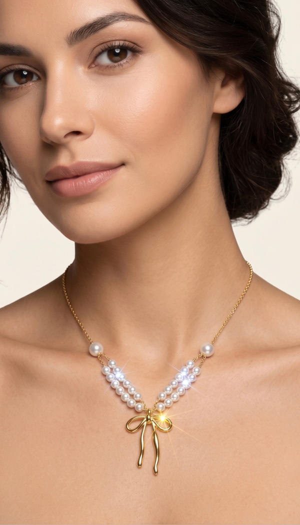 "A close-up shot of a woman wearing an elegant gold stainless steel necklace, featuring a double strand of luminous white pearls that gather into a polished gold bow pendant with a radiant sparkle."