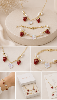 A jewelry set collage showing a gold-tone necklace and bracelet with red heart charms, white faux pearls, and clear flower-shaped crystals, plus a matching bracelet. The set is displayed on beige pedestals, on a wrist, in a white jewelry box, and on a card.